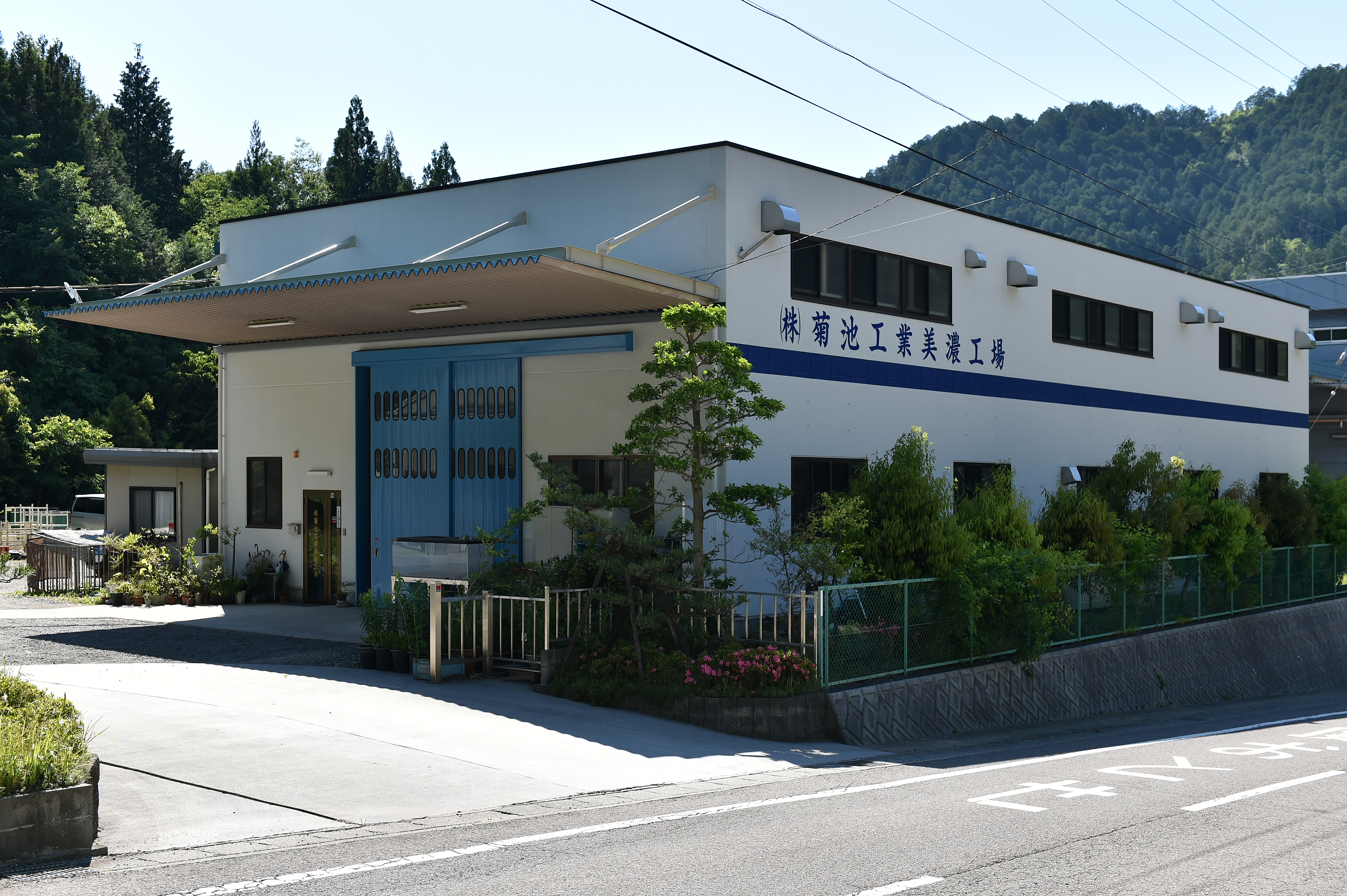 金属加工機が並ぶ工場内を通路の中央から見渡し作業動線まで分かる広角写真